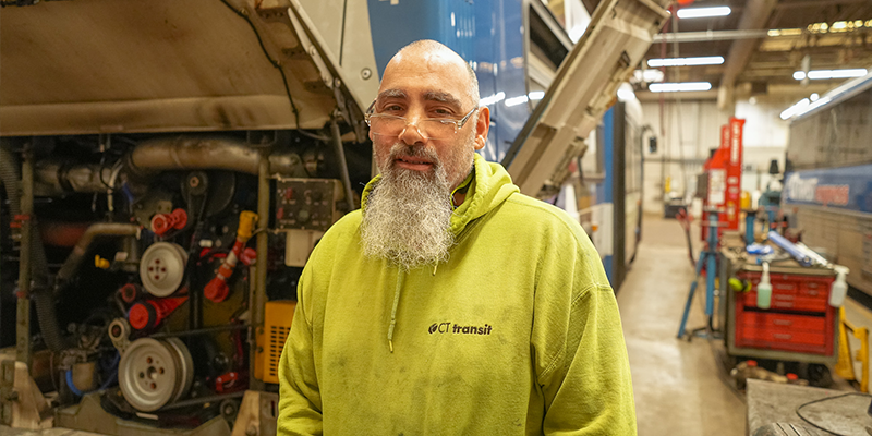 Brian Mace standing in front of a bus engine. 
